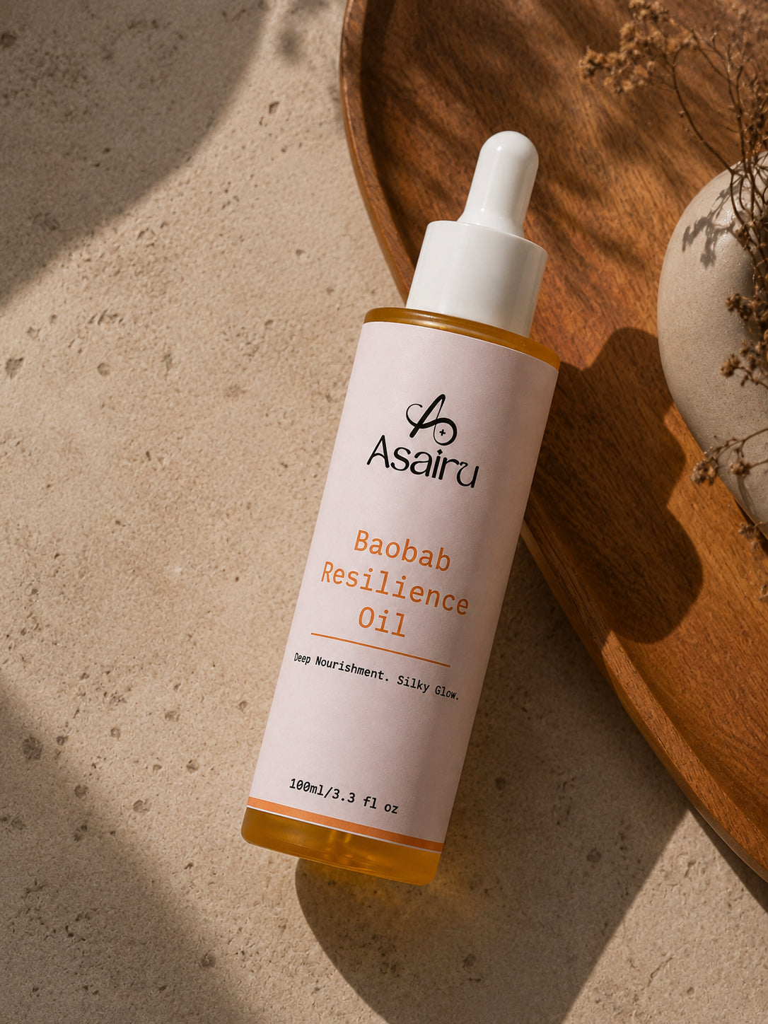Baobab Resilience Oil bottle styled with dried botanicals on stone